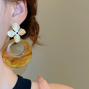 Detail of amber resin ring earring with a golden flower stud on model profile