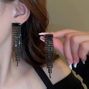 Detail view of long black rhinestone tassel earrings with a dark gothic luxury design