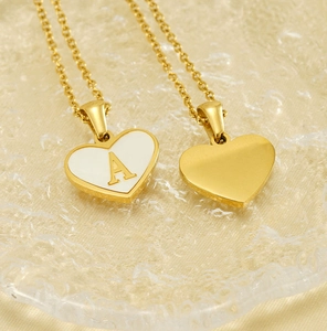 Detail of heart-shaped gold necklace with white enamel shell inlay and A-letter pendant