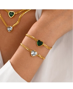 Detail of gold necklace and bracelet set with green and clear heart pendants on model