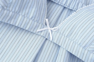 Detailed view of blue striped fabric with a white bow and delicate lace trim