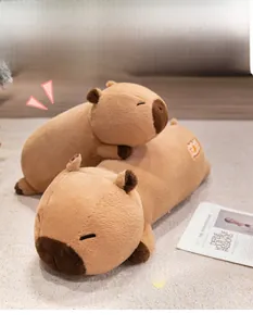 Macro view of two soft capybara plush pillows with sleeping facial expressions