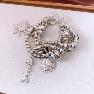 Detail of vintage multi-layer bracelet with sun, fish bone and shell charms