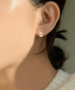 Detail of a minimalist four-prong silver stud earring with a round brilliant cut stone