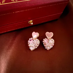 Pink heart drop earrings with gold plating and cubic zirconia on brown silk background