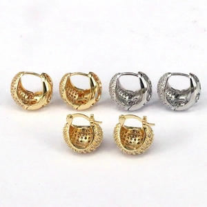 Vue macro des boucles d'oreilles huggie dorées et argentées en zircons pavés