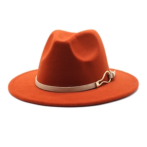 Détail d'un chapeau fedora orange rouille avec bande en cuir beige et boucle dorée