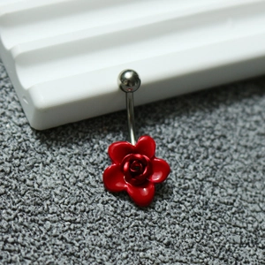Détail macro d'un piercing au nombril avec pendentif fleur rose rouge sur tige incurvée
