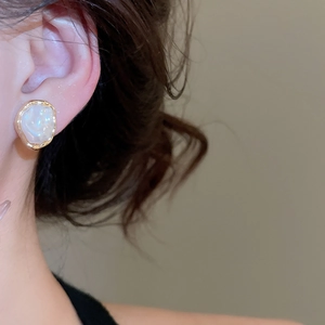 Close-up of a French vintage irregular pearl ear clip in gold on a female ear model