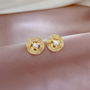 Detail shot of golden circular pearl earrings with micro-inlaid crystals on silk fabric