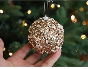 Detail of 8cm gold sequin Christmas ball with white pearls hanging on a tree