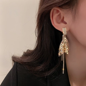 Elegant gold fishtail tassel earrings with rhinestones and metallic sequins on model