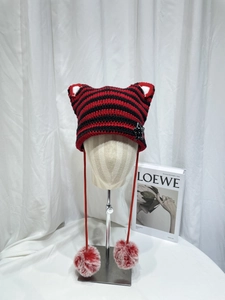 Detail of red and black striped knit cat ear hat with star sequin and fluffy pom-poms