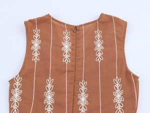 Détail de la broderie florale blanche et du zip dorsal sur une robe marron sans manches