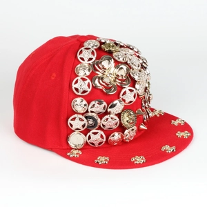 Detail of red snapback hat featuring punk metal studs and Medusa style ornaments