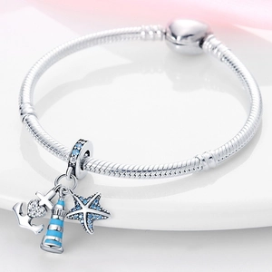 Detail of silver snake chain bracelet with blue nautical anchor and starfish charms