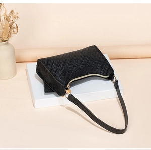 Detail of black woven pattern texture and gold zipper on minimalist hobo bag