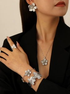 Close-up of silver floral jewelry set with textured earrings, necklace and ring on model