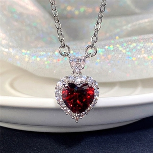 Macro shot of silver necklace with faceted red heart gemstone and sparkling pavé zircon stones