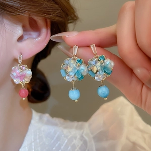 Close-up of handmade floral earrings with pearls and blue and pink crystal accents