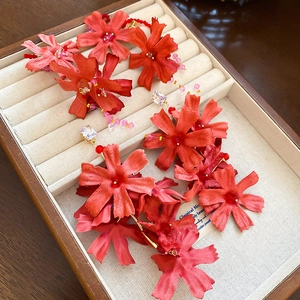 Detailed macro view of handmade red fabric flower earrings with long crystal tassels