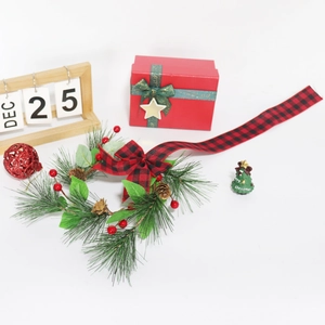 Green Christmas wreath with red plaid bow and wooden calendar on white background