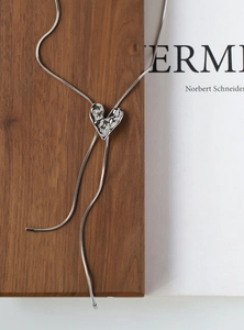 Detailed view of silver liquid metal irregular heart pendant on a thin snake chain