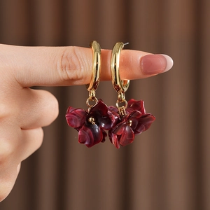 Detail of C-shaped gold hoop earrings with vintage dark red resin flower petals
