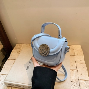 Detail of light blue PU leather saddle bag with textured finish and silver buckle