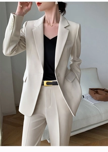 Close-up of a slim black leather belt with a metal U-buckle on an ivory suit pants