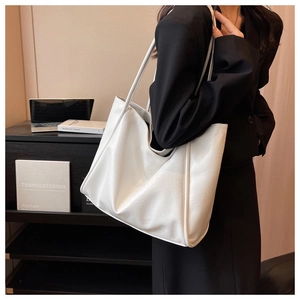 Détail d'un grand sac cabas blanc en cuir souple porté à l'épaule par le mannequin