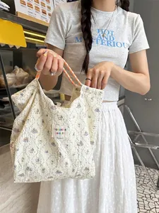 Off-white textured canvas tote bag with floral patterns and orange woven rope handles