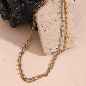 Detail of 18K gold and silver layered beaded chain necklace on natural stones