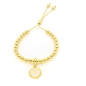 Détail du bracelet à perles dorées réglable avec breloque lettre K rose et cordon coulissant