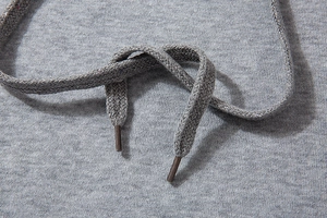 Macro view of adjustable drawstrings on a grey knitted cotton blend hoodie or sweatshirt