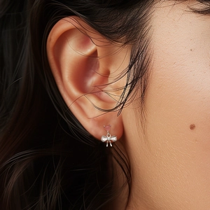 Close-up of s925 silver bow earrings with pink heart gemstone worn on ear