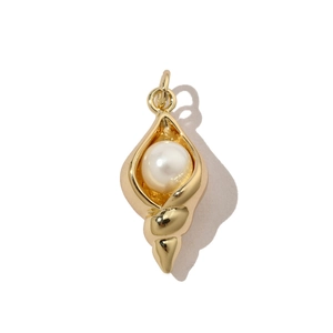 Detailed view of a golden conch shell pendant featuring a central white pearl inlay