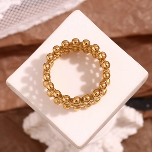 Macro detail of 18K gold plated beaded mesh cross ring on a vintage aesthetic display