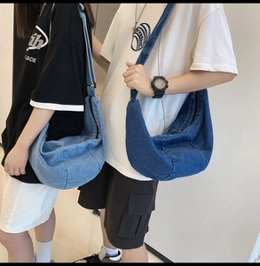 Detailed view of high-capacity crescent denim crossbody bags in dark and light blue colors