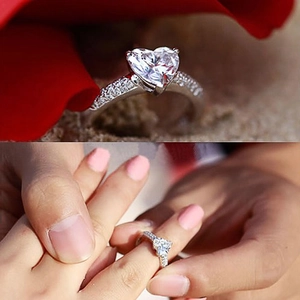 Elegant heart-shaped zircon ring on red petals with a real-life hand model view