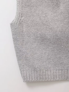 Vue détaillée du gilet en maille grise montrant la bordure côtelée et la texture
