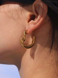 Close-up of triple-layered 18K gold-plated heart-shaped stud earrings on a model's ear