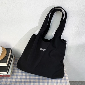 Détail d'un sac cabas noir en toile avec imprimé Simplic sur tissu à carreaux