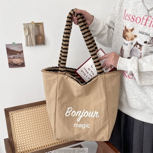 Detail of canvas tote bag with Bonjour magic print and striped plush handles