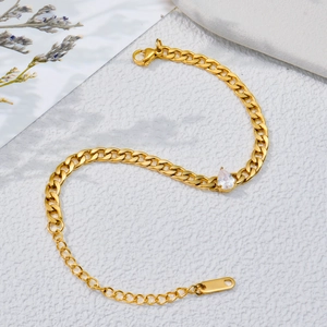 Bracelet gourmette doré orné d'un zircon étincelant en forme de poire et fermoir mousqueton