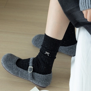 Women's black knit mid-calf socks with white bow embroidery and grey slippers