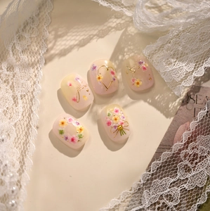 Detailed macro view of French-style floral press-on nails with 3D flower and gold accents