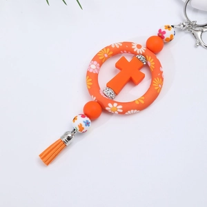 Close-up of orange silicone car charm featuring a floral cross ring and stylish tassel