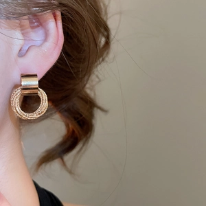 Detailed shot of a gold geometric textured earring on a model in minimalist luxury style