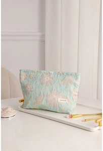 Dettaglio della trousse jacquard azzurra a fiori con etichetta tessuta su vassoio bianco